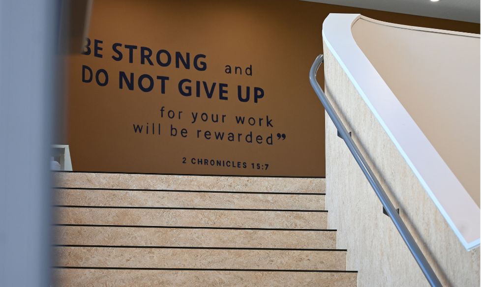 Hand-painted Be Strong and Do Not Give Up quote above a stairwell at St Columba College