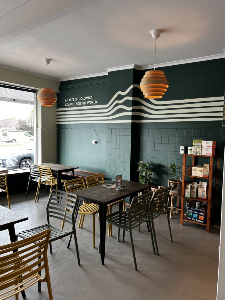 KOM Coffee Roasters coffee shop interior with green walls and mountain line mural