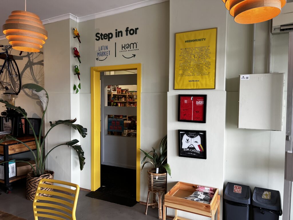 KOM Coffee Roasters feature wall with yellow door frame and framed prints