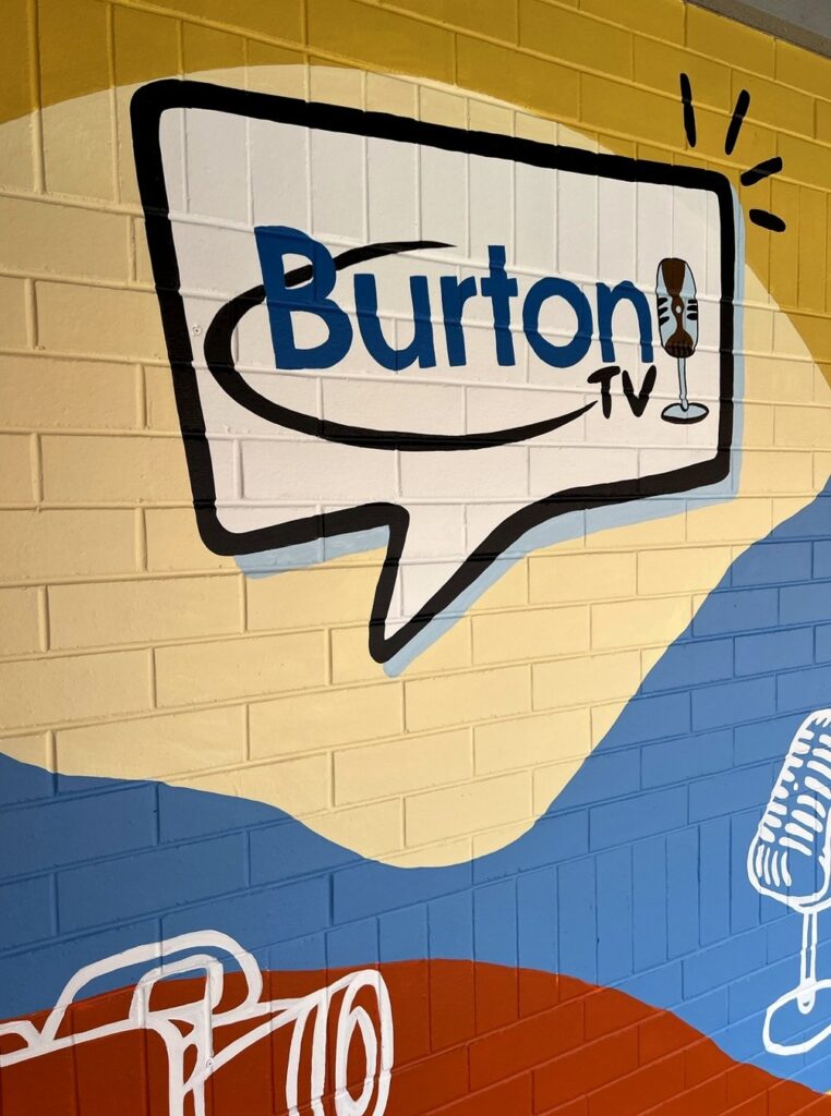 Close-up of the hand-painted Burton TV logo on brick