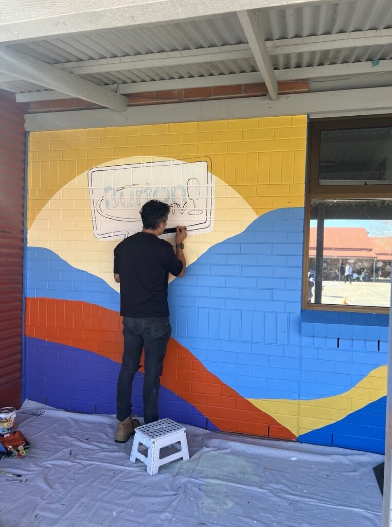 Diegodalo outlining the Burton TV logo on the school mural