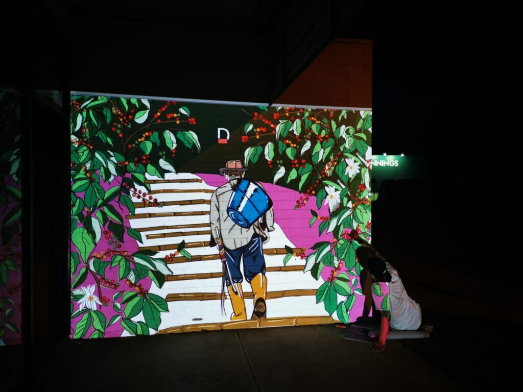The Cafetal Coffeeco mural design projected onto the wall at night to map it out