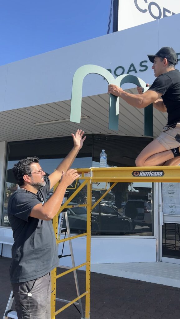 KOM Coffee Roasters owner and Diegodalo installing the facade letters together