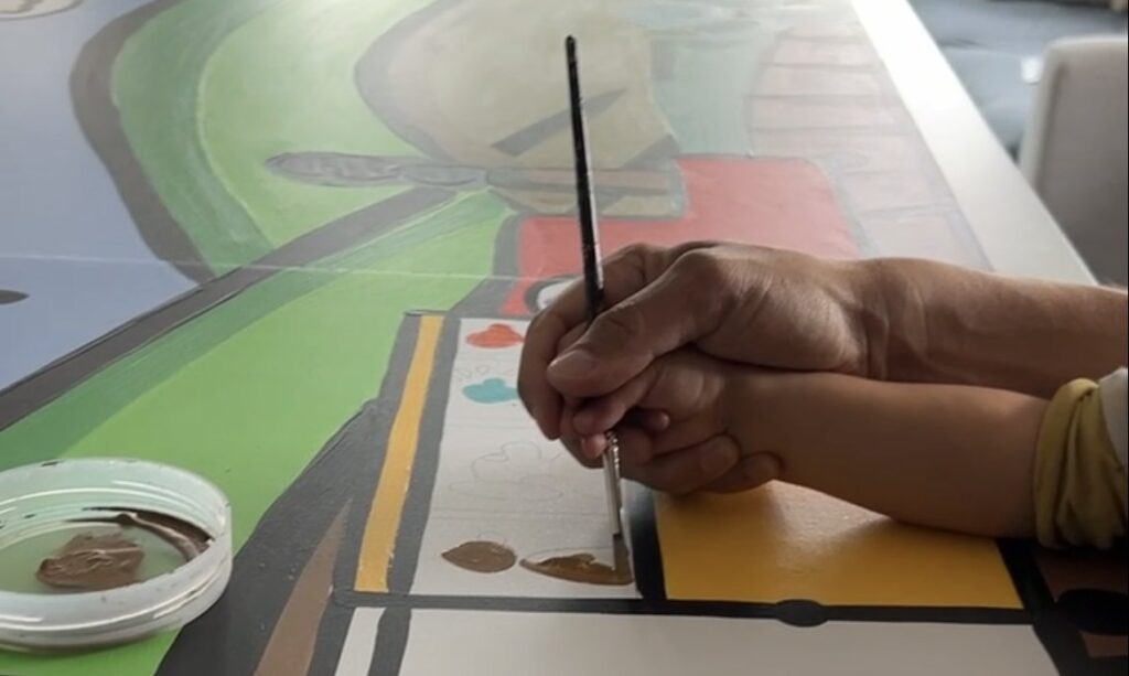 Close-up of a brush painting the train windows on the Stirling North mural panels