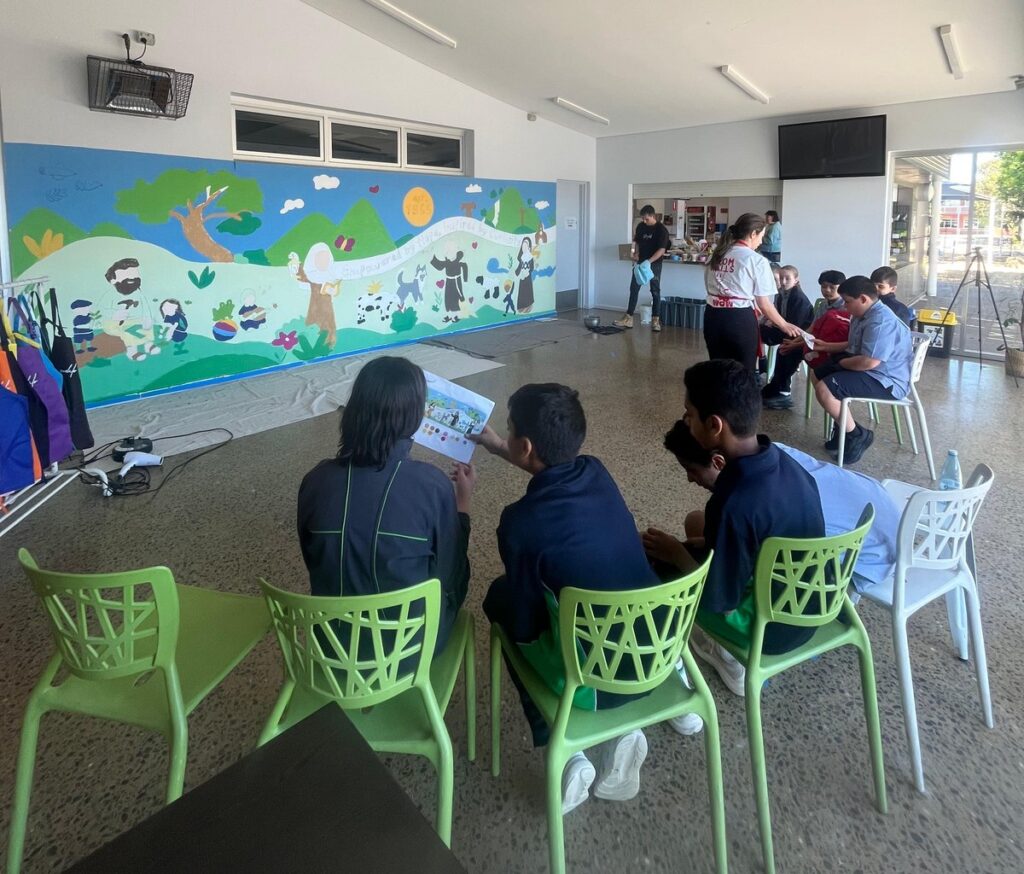 Students looking at the printed mural design during the school mural workshop at St Francis of Assisi School